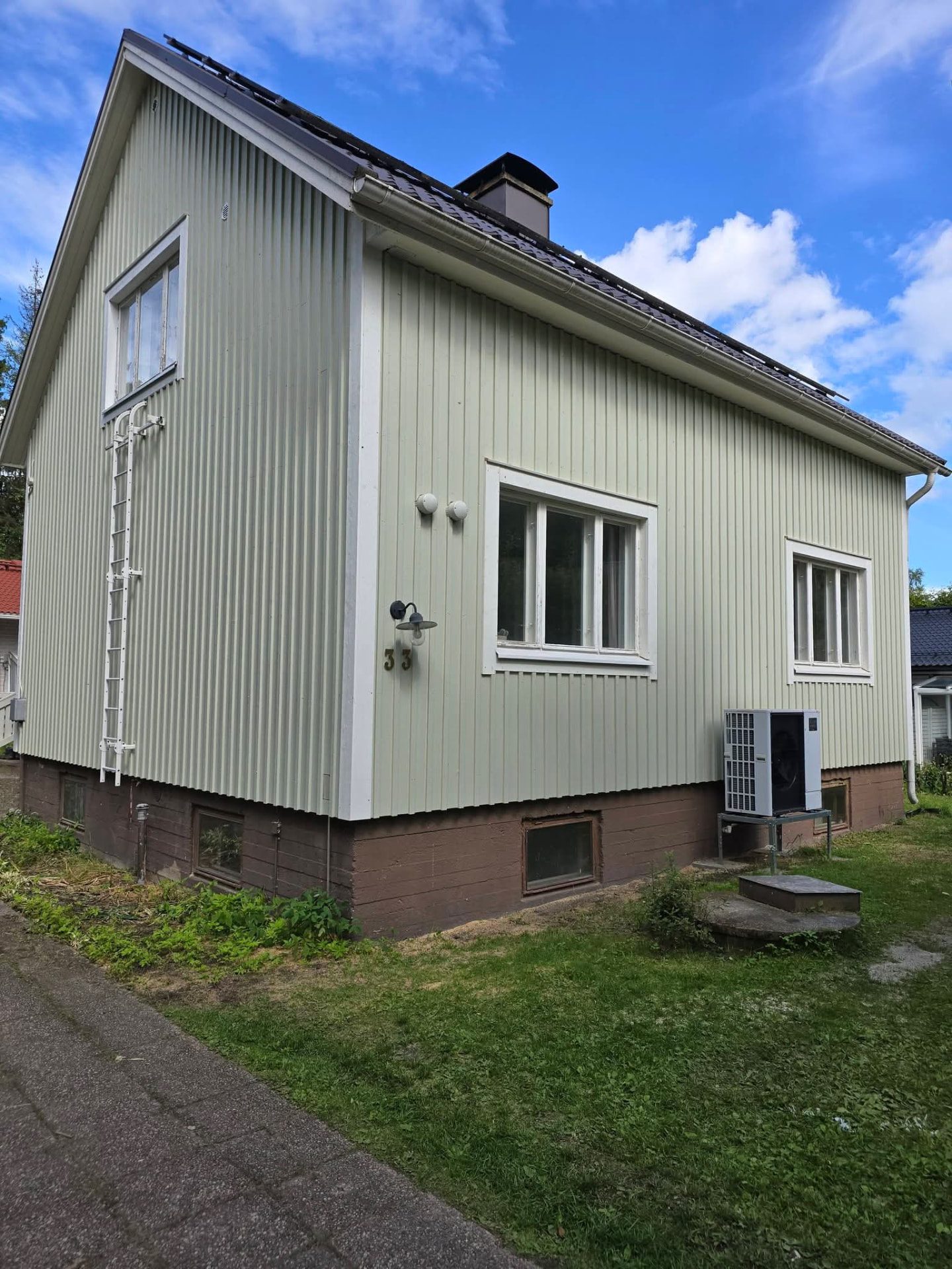 Mintunvihreä puutalo valkoisilla seinätikkailla ja talonnumerolla 33